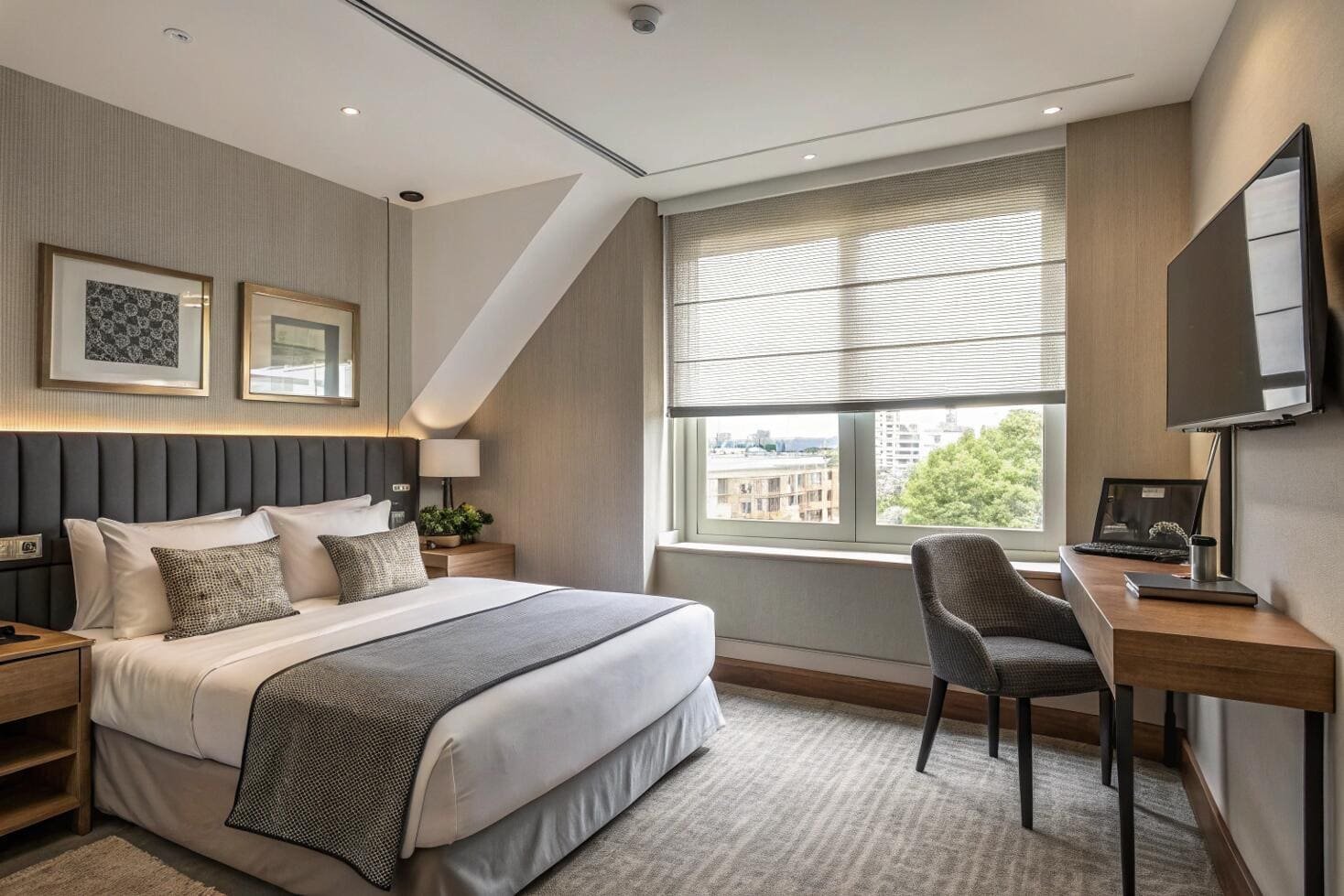Hotel bedroom with roman shade, desk, and comfy bed