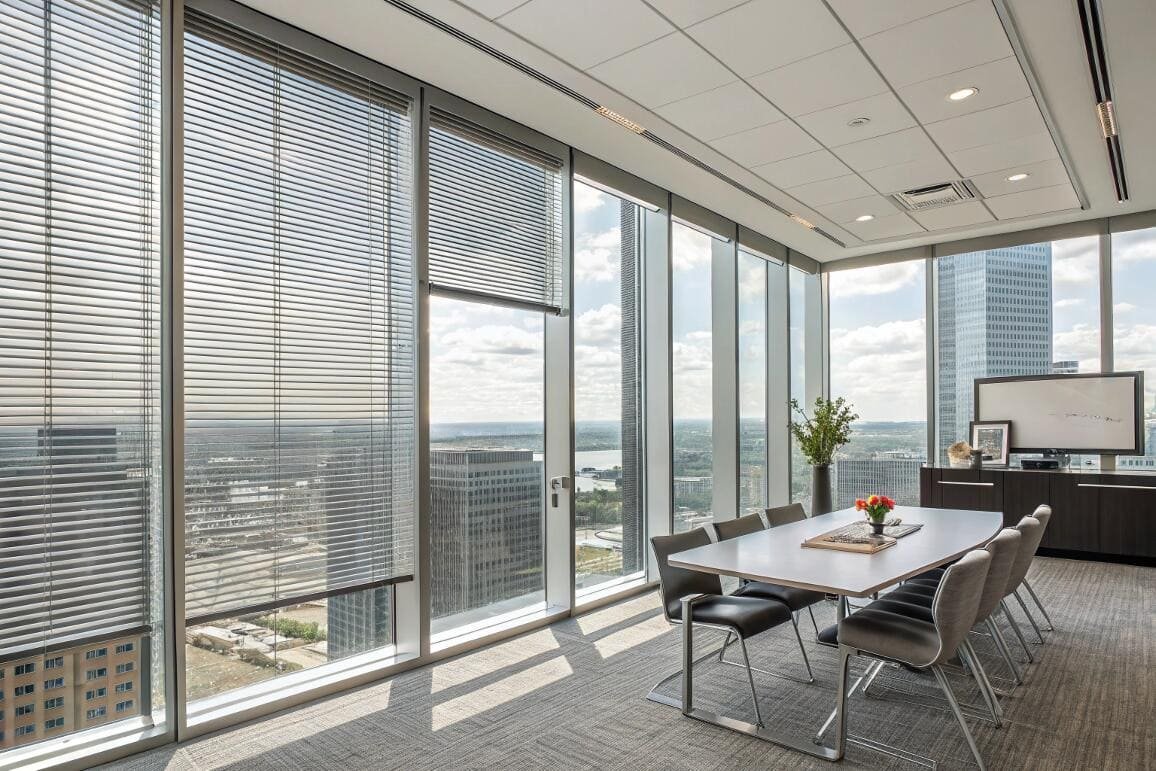 High-rise office conference room with metallic horizontal blinds and city views