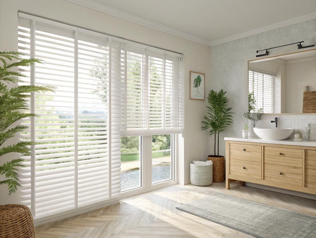 Bright bathroom with wide white faux wood blinds and a view.