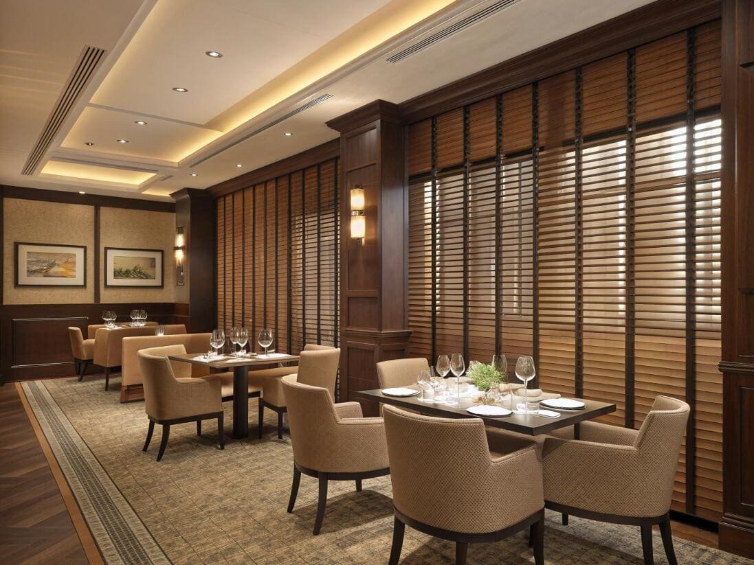 Elegant restaurant interior using wooden venetian blinds for a private, ambient dining experience.