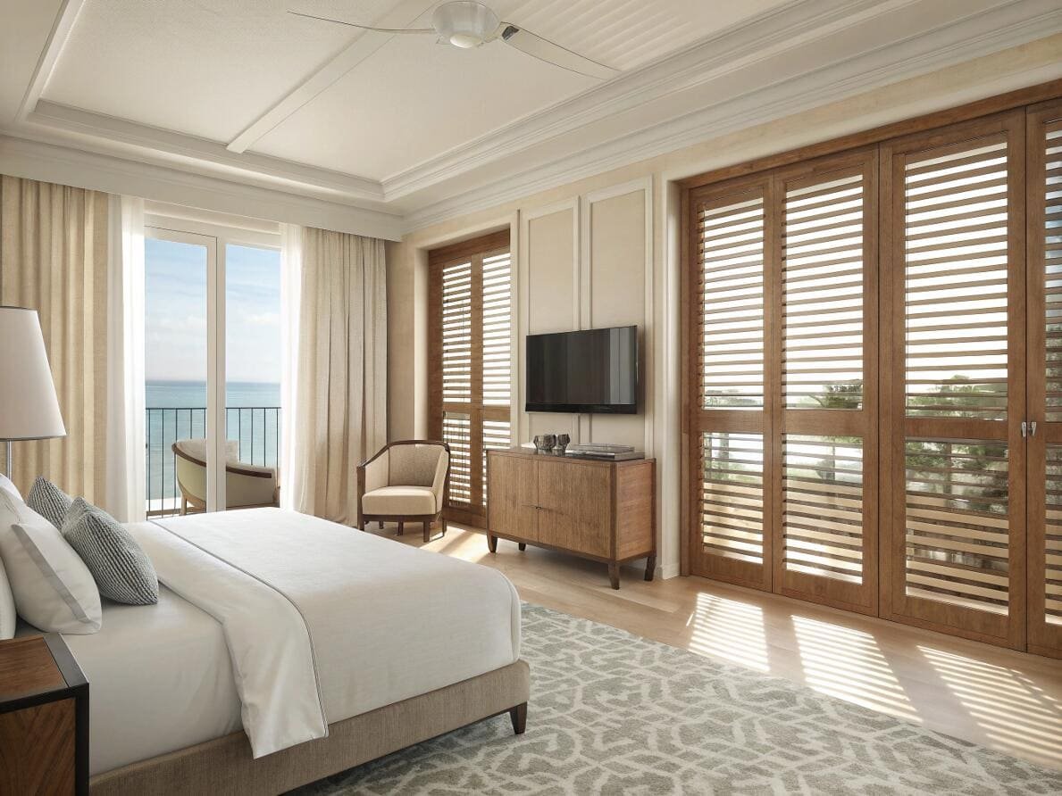 Resort-style bedroom using wood plantation shutters for windows and as a room divider.