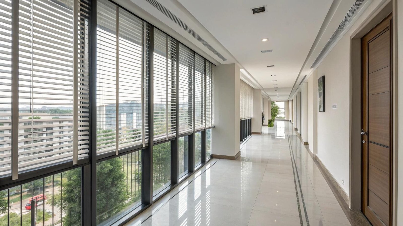 Durable white venetian blinds provide uniform light and privacy for a commercial hallway.