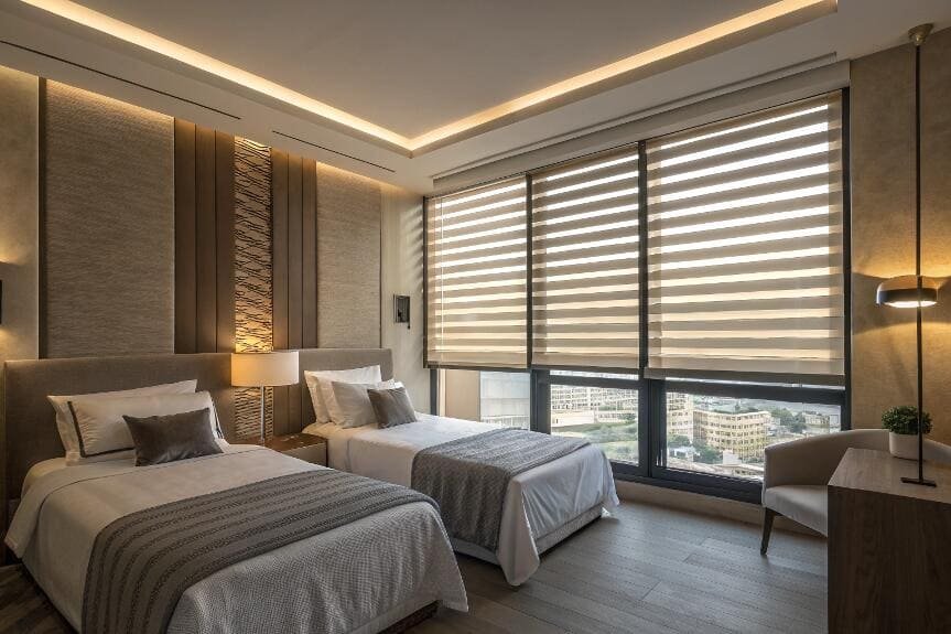 Luxurious hotel room with city view, featuring elegant zebra blinds.