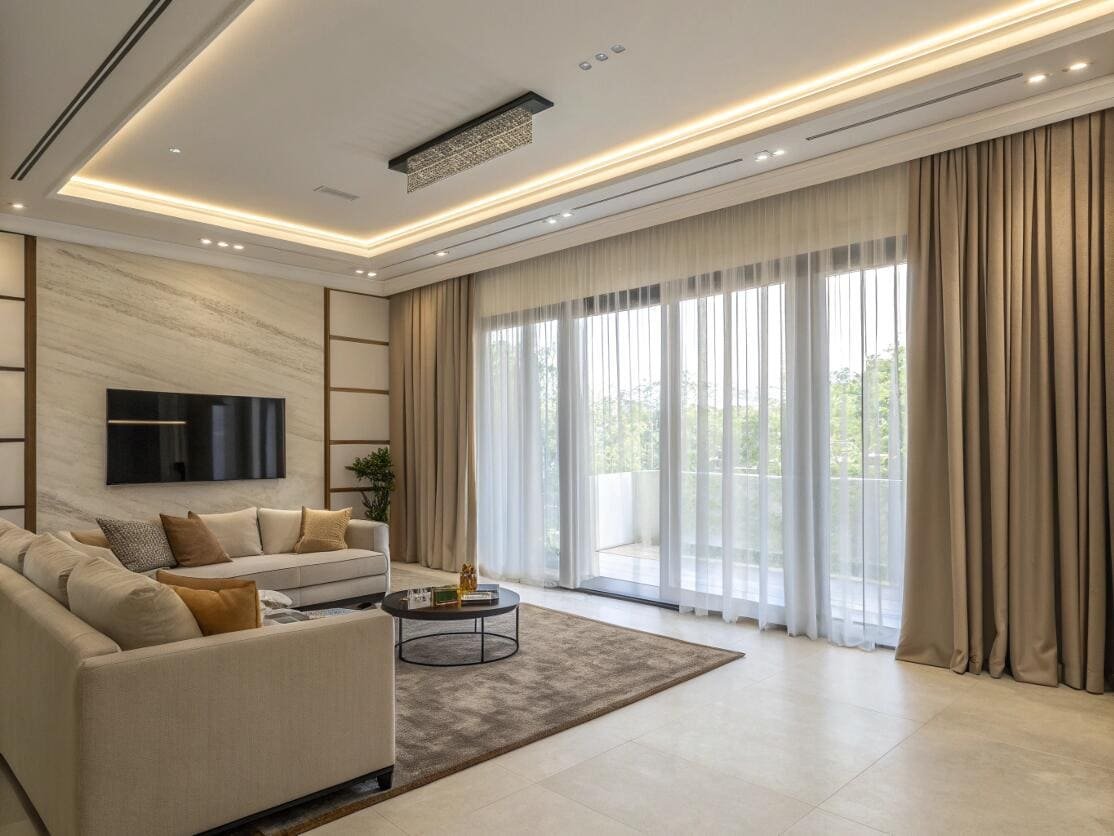 Layered sheer and beige blackout curtains dress a sliding door in a luxury living room.