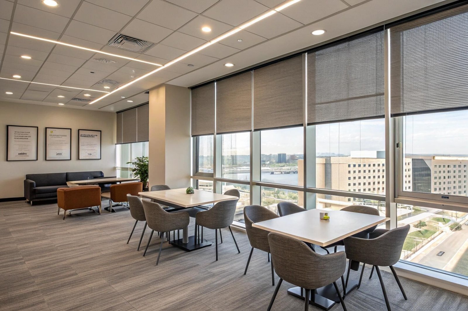 Dark solar shades reduce harsh glare and improve comfort in a modern corporate lounge.