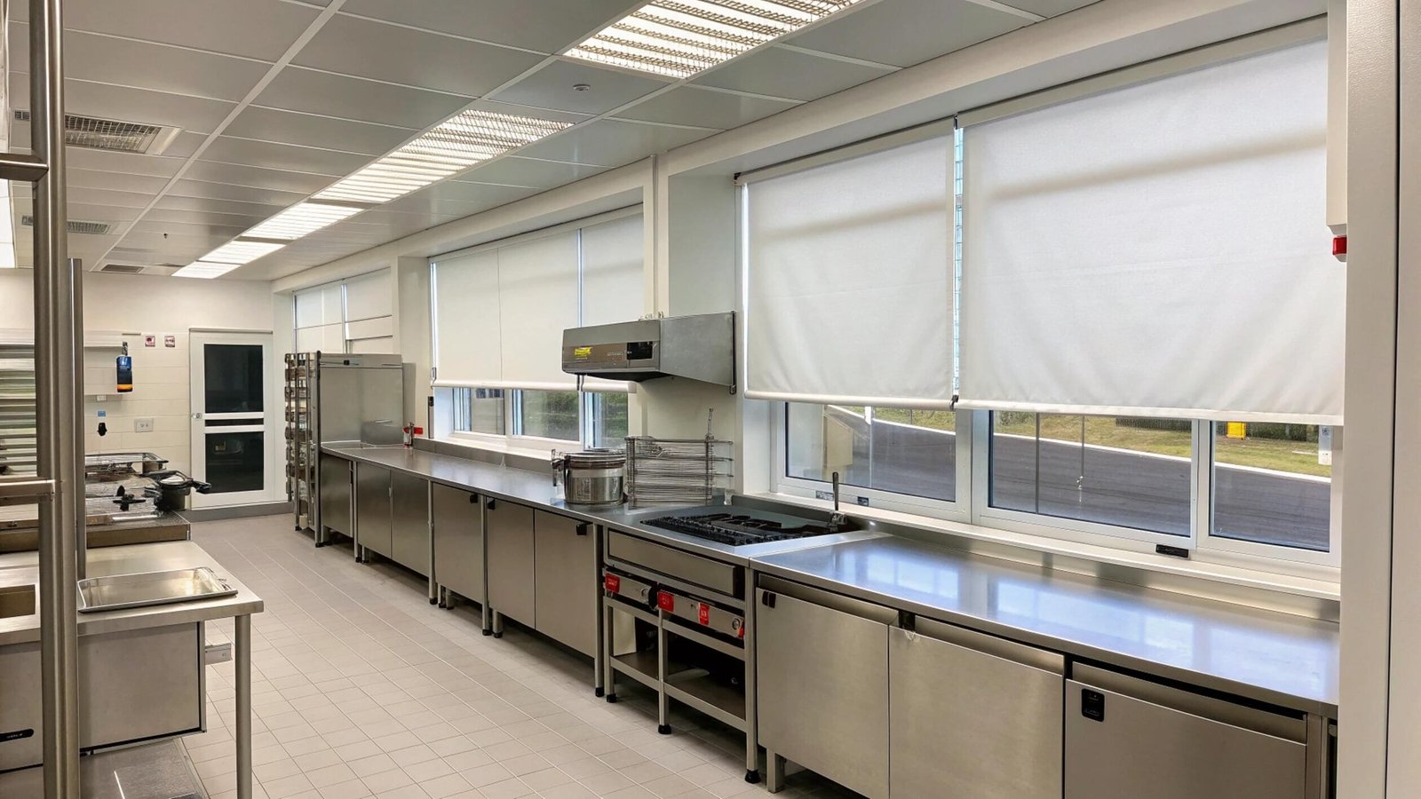 Durable, easy-to-clean white roller shades installed in a professional commercial kitchen.