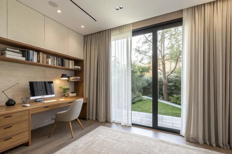 A dual-layer curtain system offers privacy and soft light for a modern home office.