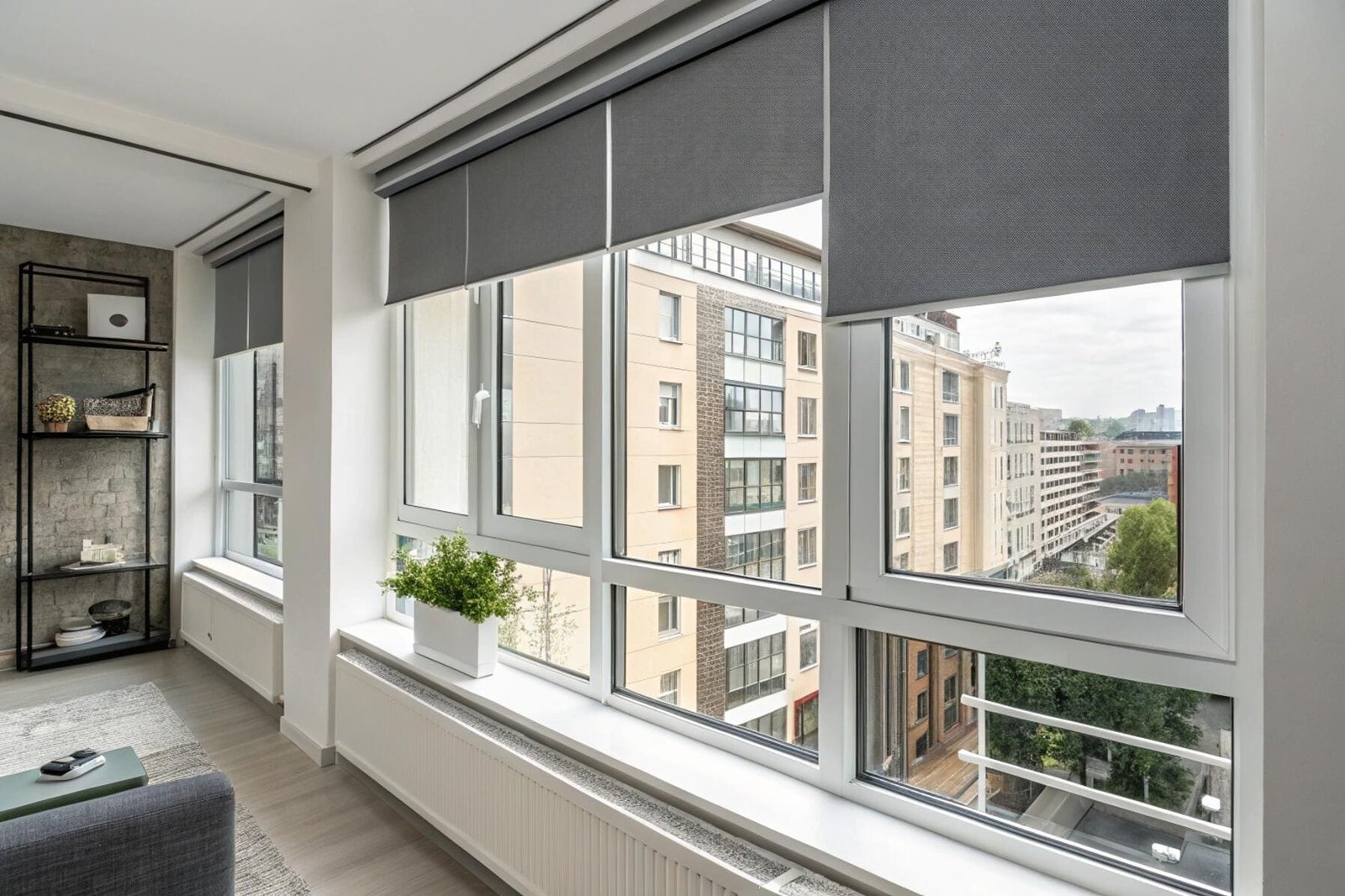 Gray roller shades with a slim cassette valance in a modern, minimalist apartment living room.