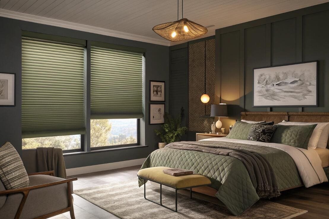 Room-darkening cellular shades in olive green create a cozy, private atmosphere in a bedroom.