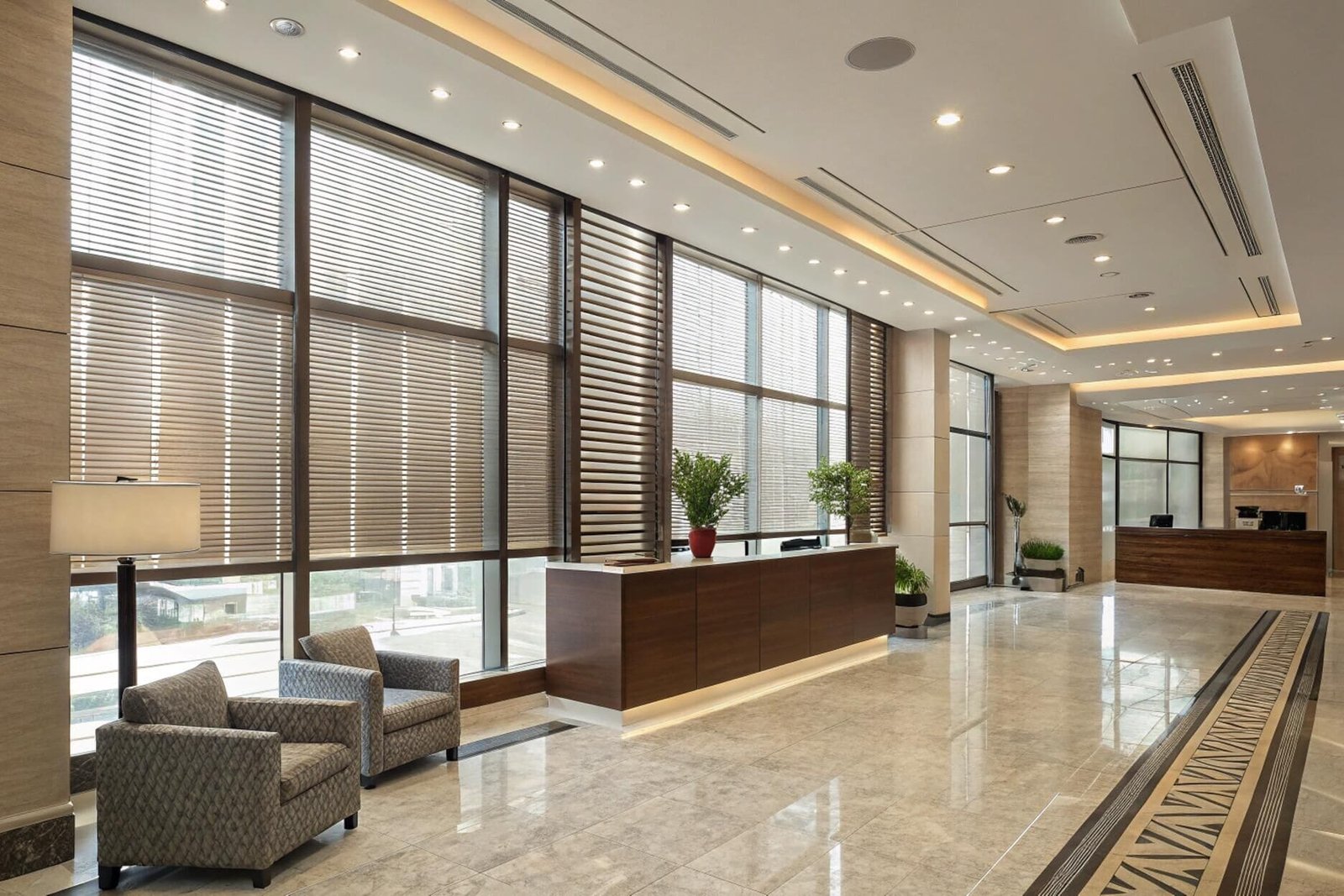 Motorized Venetian blinds manage light and privacy in a large, modern corporate lobby.