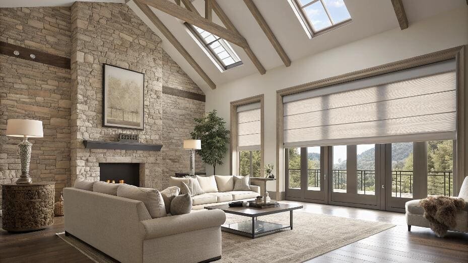 Rustic living room with stone fireplace and light-filtering Roman shades on large windows.